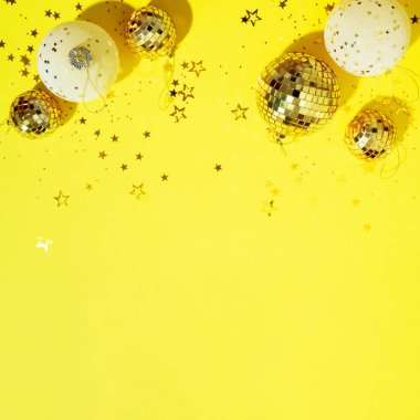 Noel kompozisyonu. Düz yerde, üst tarafta. Disko topu takısı, yıldız pırıltısı. Asgari yeni yıl partisi konsepti. Sarı zemin üzerinde noel beyazı ve altın süslemeler kopya alanı ile.