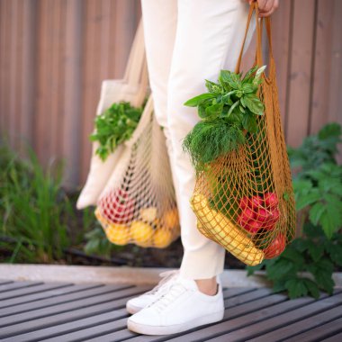 Naylon poşetsiz, ahşap arka planda sebzeli pamuk alışverişi yapan kız. Sıfır atık, plastiksiz konsept. Sürdürülebilir yaşam tarzı. Pankart.