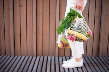 Kopya alanı ile sıfır atık kavramı. Elinde pamuk alışverişi yapan bir kadın ve sebze ve ürünlerle tekrar kullanılabilir ağ alışveriş torbaları. Çevre dostu ağ tüccarı. Sıfır atık, plastiksiz konsept.