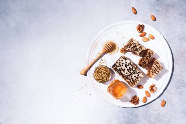 Bal ürünleri geçmişi. Bal peteği çerçevesi, arı poleni, cam kapta bal, gri beton arka planda badem fıstığı. Uzayı kopyala Üst Manzara. Sonbahar hasat konsepti. Pankart