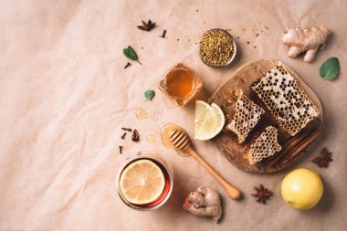 Alternatif tıp konsepti. Doğal sıcak içecekle savaşan grip malzemeleri. Uzayı kopyala Üst Manzara. Limon, zencefil, nane, bal, elma ve baharatlar kağıt üzerinde