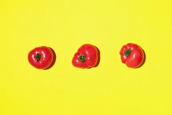 黄色の背景に赤いトマトのパターン。フラットレイアウト、トップビュー。夏のミニマルなコンセプト。ビーガン・ベジタリアンダイエット — ストック写真