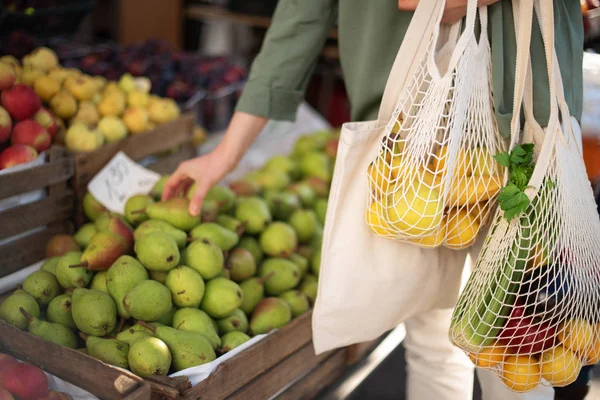 Kvinnan väljer frukt och grönsaker på bondens marknad. Noll avfall, plastfritt koncept. Hållbar livsstil. Återanvändbara ekosäckar av bomull och mesh för shopping. — Stockfoto