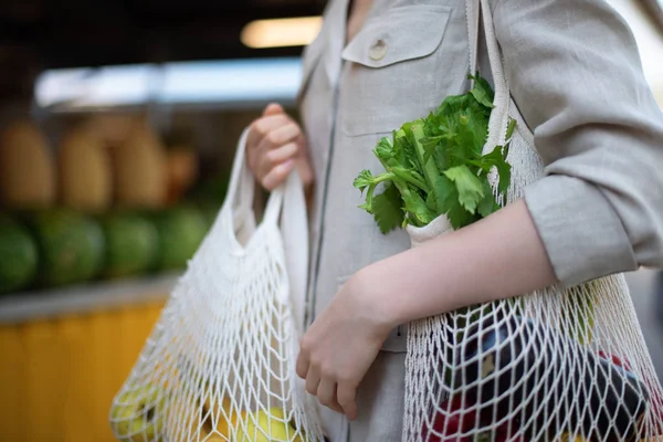 La mujer elige frutas y verduras en el mercado de agricultores. Cero residuos, concepto libre de plástico. Estilo de vida sostenible. Bolsas ecológicas de algodón y malla reutilizables para ir de compras . — Foto de Stock