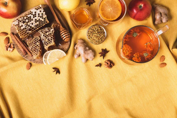 Autumn harvest concept. Set of honey and bee products, apple, lemon, calendula tea, spices on yellow background. Immune system support with alternative medicine