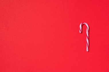 Kırmızı arka planda fotokopi alanı olan Noel şekeri kamışı. Üst Manzara. Noel ve Yeni Yıl 'da tebrik kartı. Minimum festival konsepti