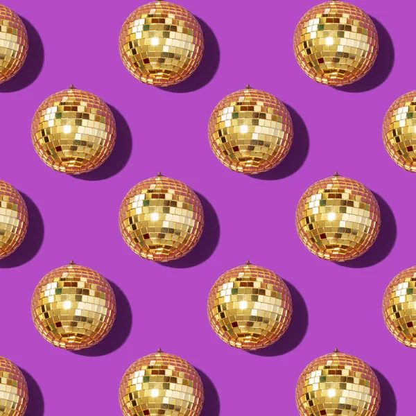 New year baubles. Shiny gold disco balls on violet background. Pop disco style attributes, retro concept. Creative Christmas pattern. Flat lay, top view.