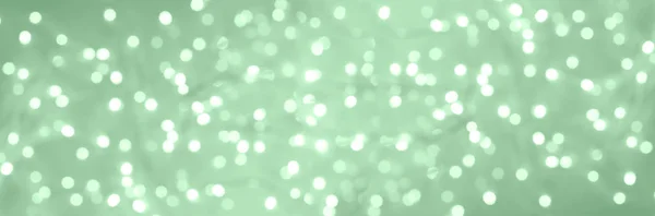 Świąteczne błyszczące lampki świąteczne. Abstrakcyjne betonowe tło w modnym kolorze neo mennicy. Zamazany baner z bokeh. — Zdjęcie stockowe