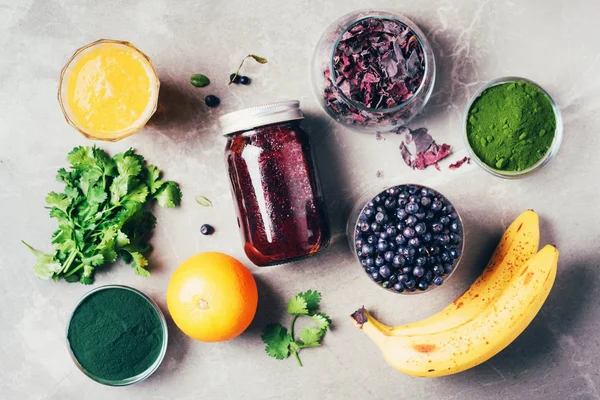 Blueberries, bilberry, barley grass, spirulina, orange juice, dulse, cilantro on marble background. Top view. Healthy eating, alkaline diet, vegan concept. Ingredients of heavy metals detox smoothie. — Stock Photo, Image