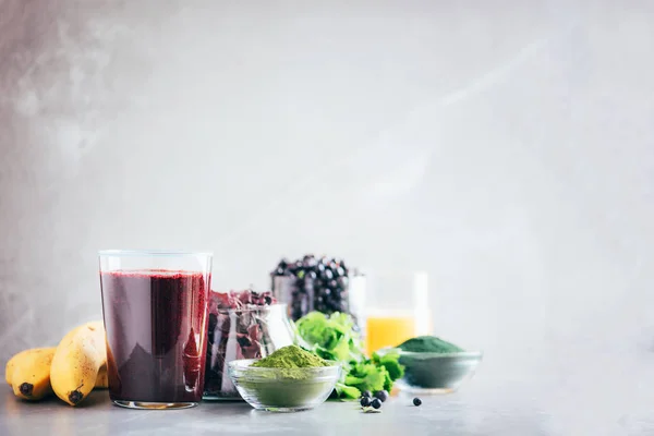 Verse bosbessen, bosbessen, gerstegras sap, spirulina, sinaasappelsap, dulse en cilantro op marmeren achtergrond. Zware metalen ontgiften smoothie. Gezond eten, alkalisch dieet, veganistisch concept. — Stockfoto