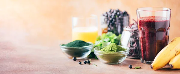 Gezond eten, alkalisch dieet, veganistisch concept. Bosbessen, bosbessen, gerstegras, spirulina poeder, sinaasappelsap, dulse, koriander op marmeren achtergrond. Ingrediënten voor zware metalen detox smoothie. — Stockfoto