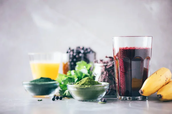 Alimentación saludable, dieta alcalina, concepto vegano. Arándanos, arándanos, jugo de hierba de cebada, espirulina, jugo de naranja, dulse y cilantro sobre fondo de mármol. Ingredientes para batido de desintoxicación de metales pesados . — Foto de Stock