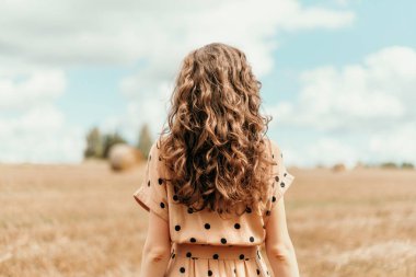 Hasat edilen tarlada saman balyalarıyla dikilen genç bir kadın. Fotokopi alanı olan tarım arka planı. Yaz ve sonbahar hasat konsepti. Şükran Günü