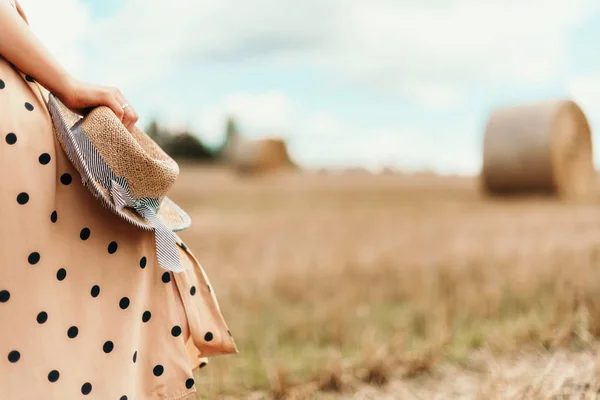 Jovem mulher segurando chapéu de palha no campo de trigo. Agricultura fundo com espaço de cópia. Conceito de colheita de verão e outono. Campo colhido com fardos de palha . — Fotografia de Stock