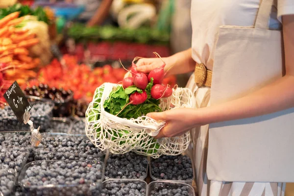 La mujer elige frutas y verduras en el mercado de agricultores. Cero residuos, concepto libre de plástico. Estilo de vida sostenible. Bolsas ecológicas de algodón y malla reutilizables para ir de compras . — Foto de Stock