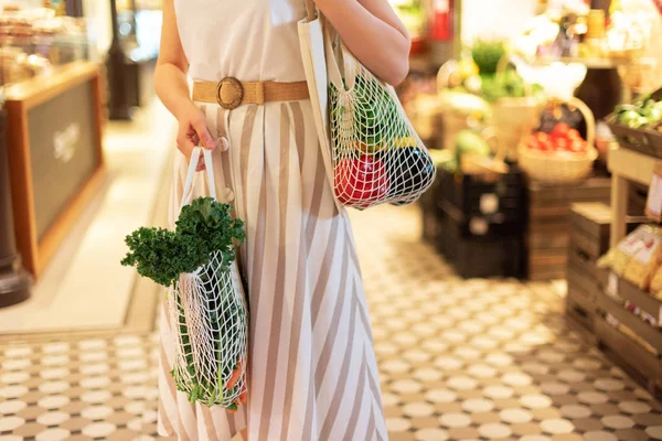 Chica sosteniendo bolsa de compras de malla y comprador de algodón con verduras sin bolsas de plástico, fondo de madera. Cero residuos, concepto libre de plástico. Estilo de vida sostenible. Banner. — Foto de Stock