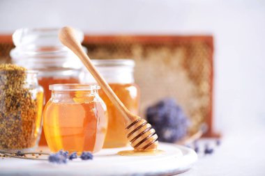 Arı poleni tanecikleri, ahşap damlalı bal kavanozu, gri arka planda bal peteği. Uzayı kopyala Sonbahar hasat konsepti