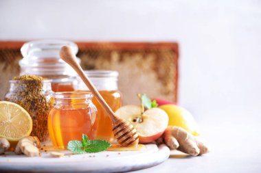 Alternatif tıp konsepti. Doğal sıcak içecekle savaşan grip malzemeleri. Uzayı kopyala Limon, zencefil, nane, bal, elma ve baharatlar gri arka planda
