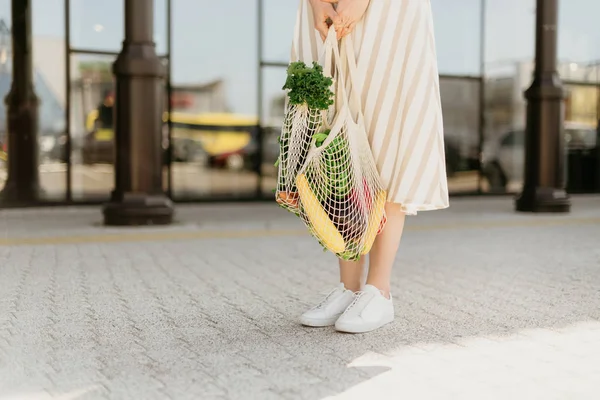 Chica sosteniendo bolsa de compras de malla y comprador de algodón con verduras sin bolsas de plástico, fondo de madera. Cero residuos, concepto libre de plástico. Estilo de vida sostenible. Banner. —  Fotos de Stock