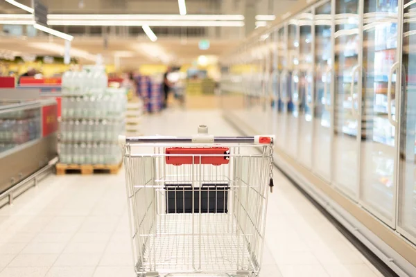 Empty red shopping cart in supermarket interior. Copy space. Sustainable lifestyle. Sale, discount concept — Stock Photo, Image
