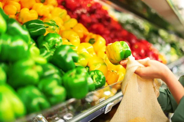 Mulher escolhe frutas e legumes no mercado de agricultores. Zero desperdício, conceito livre de plástico. Estilo de vida sustentável. Sacos ecológicos de algodão e malha reutilizáveis para compras . — Fotografia de Stock