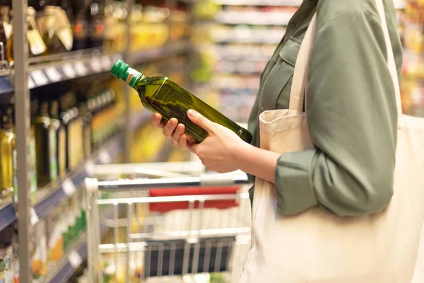 Девушка выбирает бутылку масла в продуктовом отделе супермаркета. Принято. Здоровая диета. Устойчивый образ жизни . — стоковое фото
