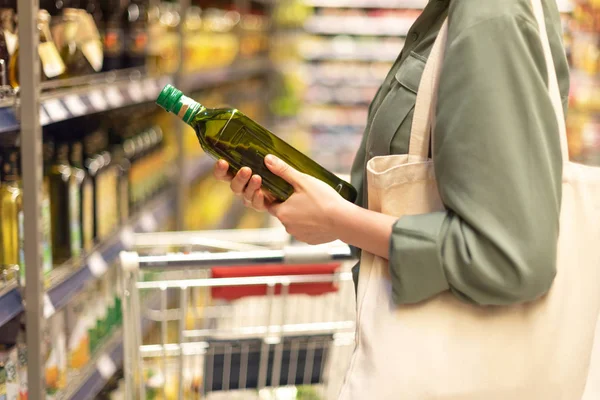 Girl choosing bottle of oil in grocery section of supermarket. Copy space. Healthy diet concept. Sustainable lifestyle. — Stock Photo, Image