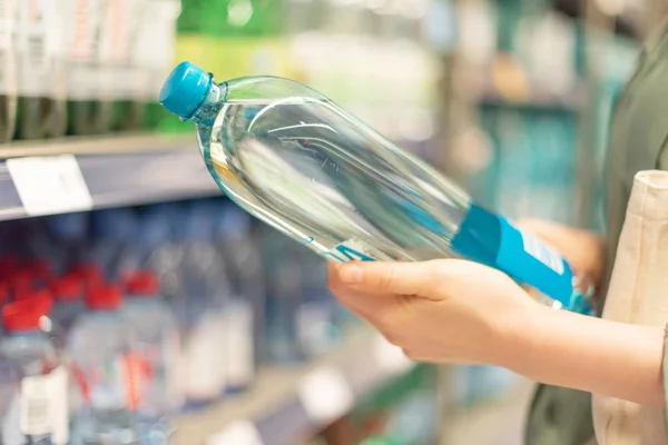 Girl choosing bottle of drinking water in grocery section of supermarket. Copy space. Water balance and body hydration. Healthy diet concept. Sustainable lifestyle. — Stock Photo, Image