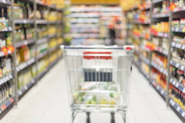 Bulanık süpermarket arka planında yiyecek dolu bir market arabası. Uzayı kopyala Sürdürülebilir yaşam tarzı. İndirim, indirim konsepti