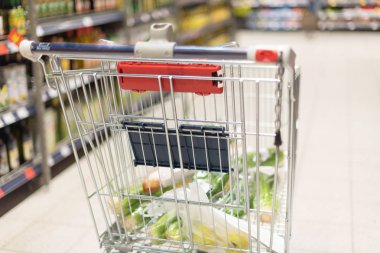 Bulanık süpermarket arka planında yiyecek dolu bir market arabası. Uzayı kopyala Sürdürülebilir yaşam tarzı. İndirim, indirim konsepti