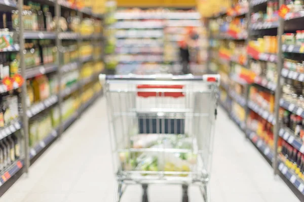 Grocery shopping cart full with food at blurred supermarket background. Copy space. Sustainable lifestyle. Sale, discount concept — Stock Photo, Image