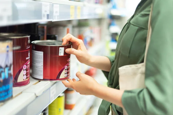 Woman shopping in hardware store. Girl is choosing paint in paint store. Banner with copy space — Stock Photo, Image