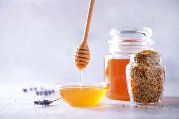 Bee pollen granules, honey jar with wooden dropper, honeycomb on grey backdrop. Copy space. Autumn harvest concept — 스톡 사진