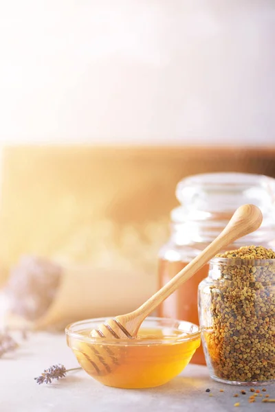 Bee pollen granules, honey jar with wooden dropper, honeycomb on grey backdrop. Copy space. Autumn harvest concept — 스톡 사진