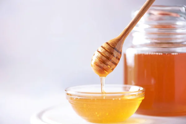 Мед капает с деревянной ложки меда в банку на сером фоне. Принято. Концепция осеннего сбора . — стоковое фото