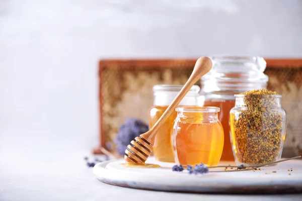 Bienenpollengranulat, Honigglas mit Holztropfen, Wabe auf grauem Hintergrund. Kopierraum. Herbsterntekonzept — Stockfoto