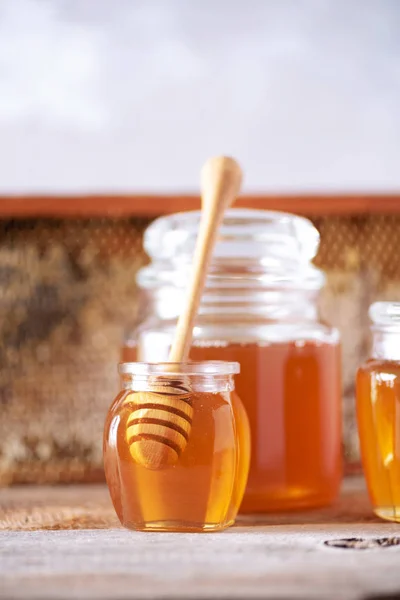 Sfondo prodotti miele. Struttura a nido d'ape, granuli di polline d'api, miele in vaso di vetro, mandorle su fondo grigio cemento. Ricevuto. Concetto di raccolta autunnale . — Foto Stock