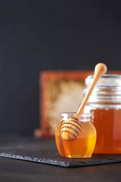 Frasco de mel, favo de mel e colher de madeira em jarra no fundo preto. Espaço para cópia. Conceito de colheita de outono . — Fotografia de Stock