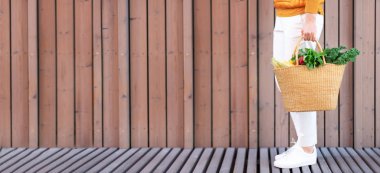 Kopya alanı ile sıfır atık kavramı. Sebzeli saman sepeti taşıyan bir kadın, ürünler. Çevre dostu alışverişçi. Sıfır atık, plastiksiz konsept.