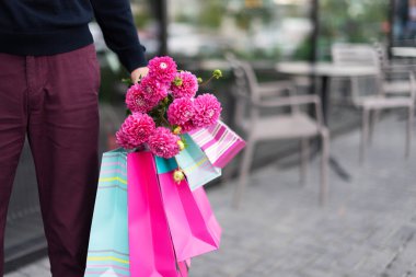 Sevgilisi kafenin yanında kız arkadaşını bekliyor elinde çiçek buketi ve bir sürü pembe hediye paketi tutuyor. Doğum günü partisi ya da romantik randevu için hazır mısın?.