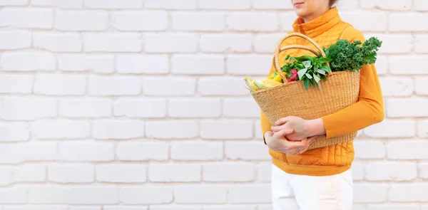 Zero waste concept with copy space. Woman holding straw basket with vegetables, products. Eco friendly shopper. Zero waste, plastic free concept.