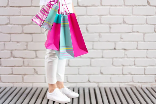 Concepto de compras. Chica sosteniendo montón de bolsas de compras con compras cerca de fondo de ladrillo. Copiar espacio. Venta, descuento, concepto de viernes negro. Centro comercial y outlet —  Fotos de Stock