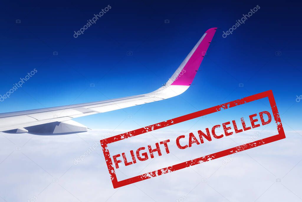 Wing of airplane flying above the clouds in the sky with text flight cancelled. Flight cancellation due to impact of coronavirus COVID-19. Stay home. Airline crisis. Travel, vacation ban concept