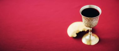 Mayasız ekmek, şarap kadehi, kırmızı arka planda gümüş şarap kadehi. Komünyon hala hayattır. İsa 'nın kurban edilişini hatırlatmak için Hıristiyan cemaati konsepti. Paskalya Hamursuzluğu.