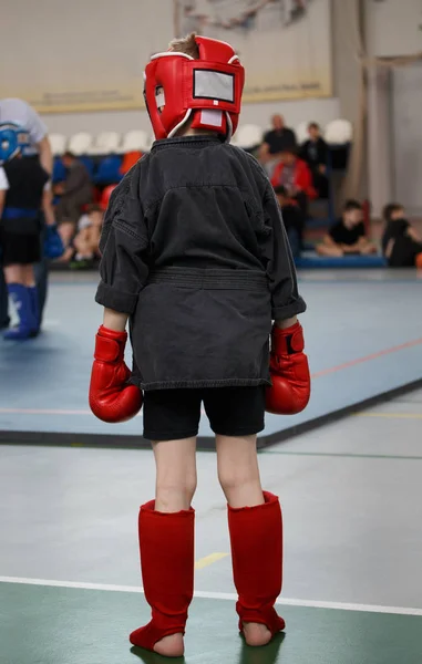 Jovem rapaz desportista lutador em luvas e um capacete protetor antes de entrar no ringue — Fotografia de Stock