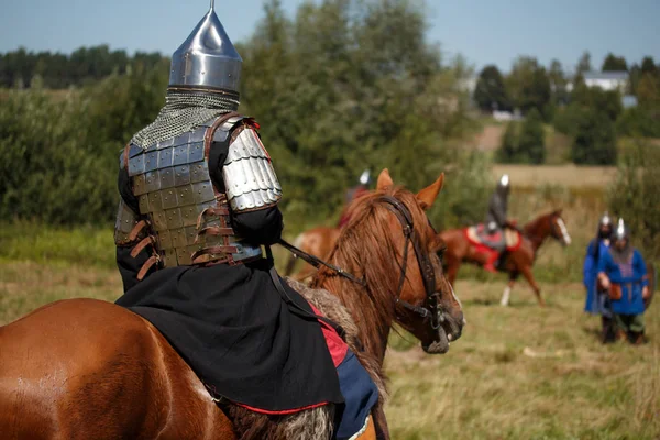 Reconstruction. Medieval armored knight on horse. Equestrian soldier in historical costume. Reenactor is in the field — Stock Photo, Image
