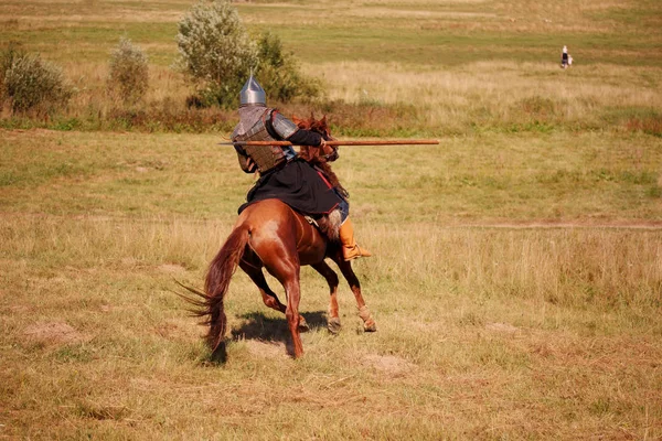 Středověké obrněný rytíř s kopím na koni dohání prchající žena a její děti. Jezdecké voják v historických kostýmech — Stock fotografie