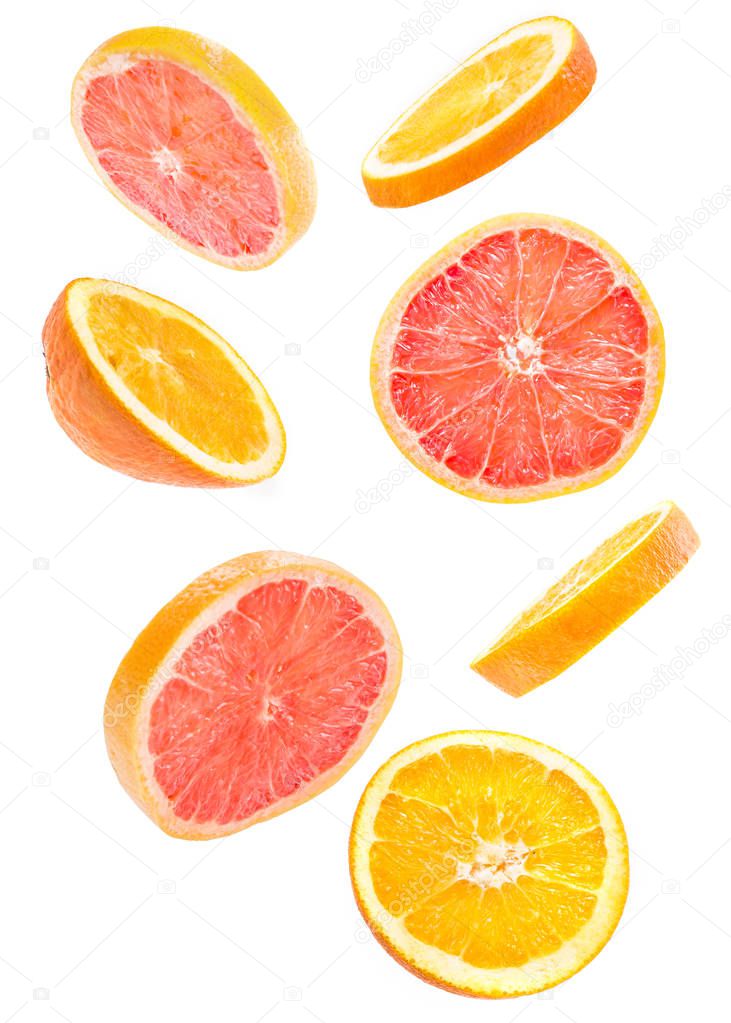 Creative concept with flying citrus fruit. Sliced grapefruit and orange isolated on white background. Levity fruit floating in the air