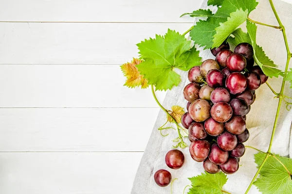 taze yeşil yaprakları ve beyaz ahşap arka planda düz masa örtüleri ile üzüm demet üstten görünüm yatıyordu. yaz meyve kavramı