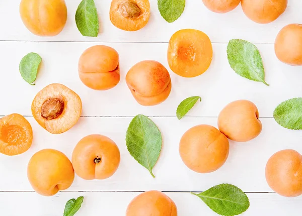 üstten görünüm taze kayısı desen beyaz tahta arka plan ile düz yaprakları üzerinde yatıyordu